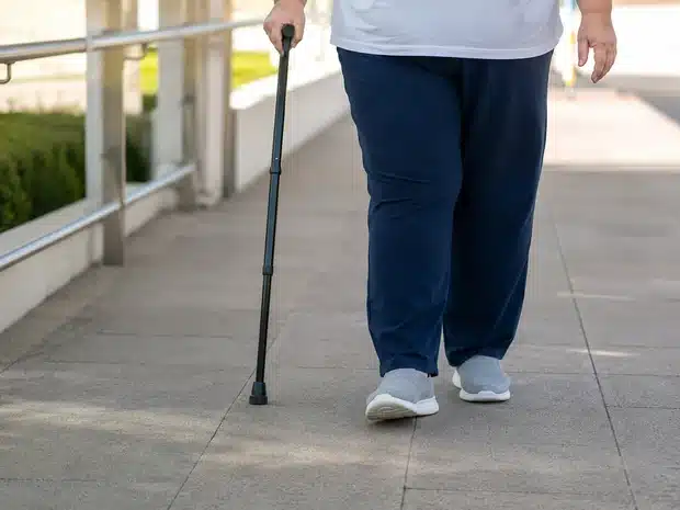 Person with obesity walking with a cane in an accessible environment