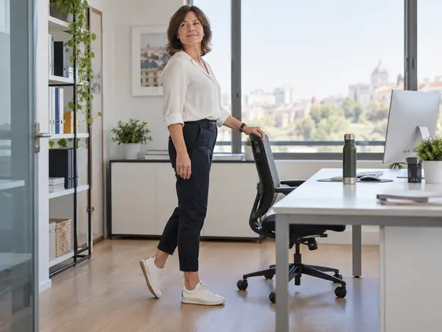 Mujer realizando una pausa activa junto a su mesa de trabajo